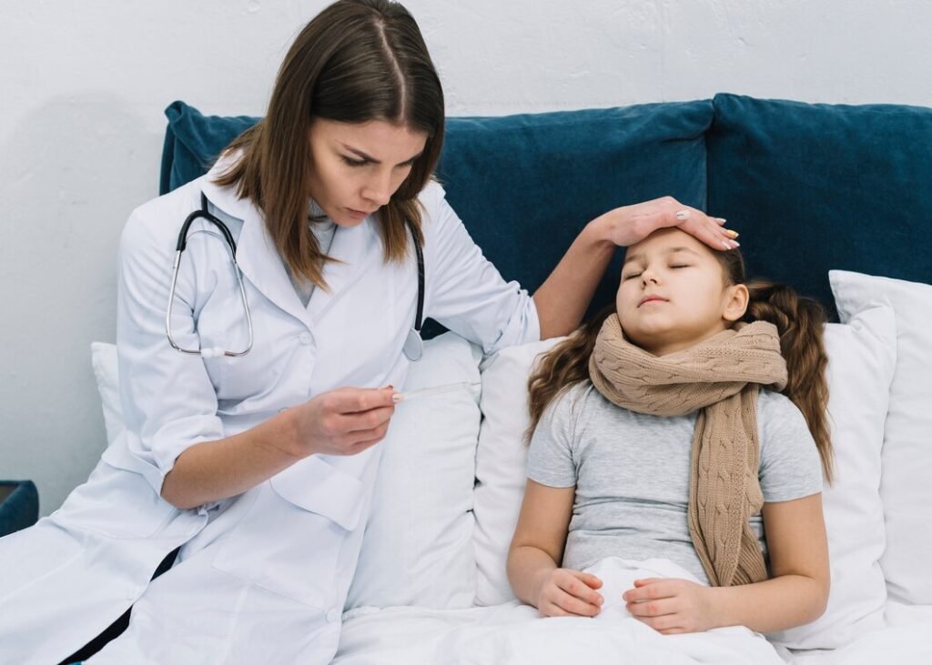 Close up photo of a female doctor sitting beside a young patient while checking a thermometer during a medical visit. Image used by a medical clinic in San Bernardino to represent pediatric care