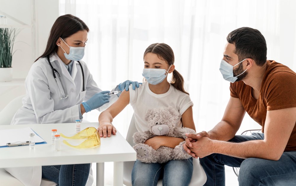 Photo of a healthcare provider administering vaccinations to an adult and a child in a clinical setting. Image used by a medical clinic in San Bernardino to represent immunization and preventive care.